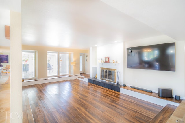 unfurnished living room featuring a fireplace, baseboards, and wood finished floors