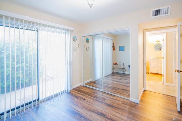 hall with visible vents, plenty of natural light, baseboards, and wood finished floors