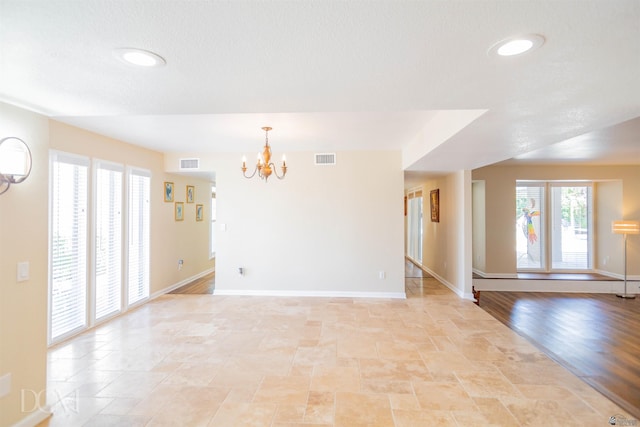 empty room with baseboards, visible vents, and a notable chandelier