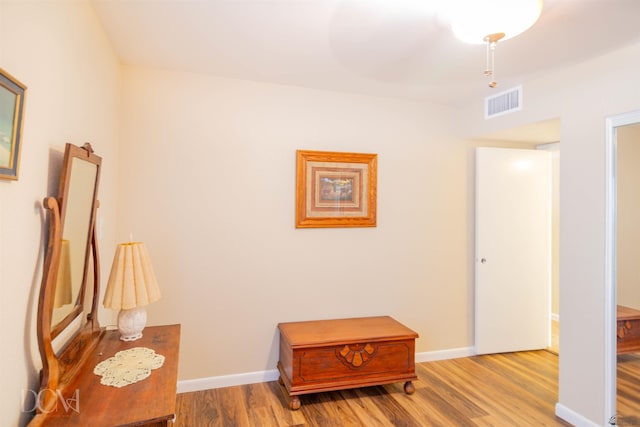 hallway featuring wood finished floors, visible vents, and baseboards