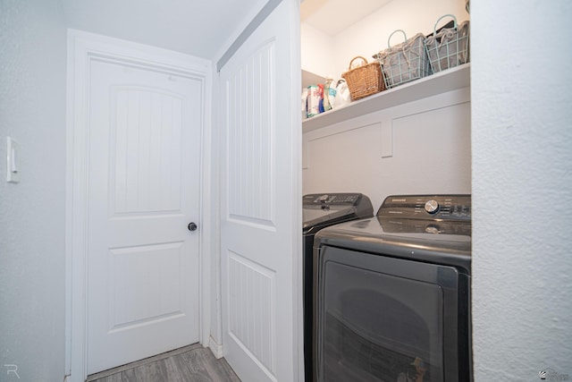 clothes washing area featuring hardwood / wood-style flooring and washing machine and dryer