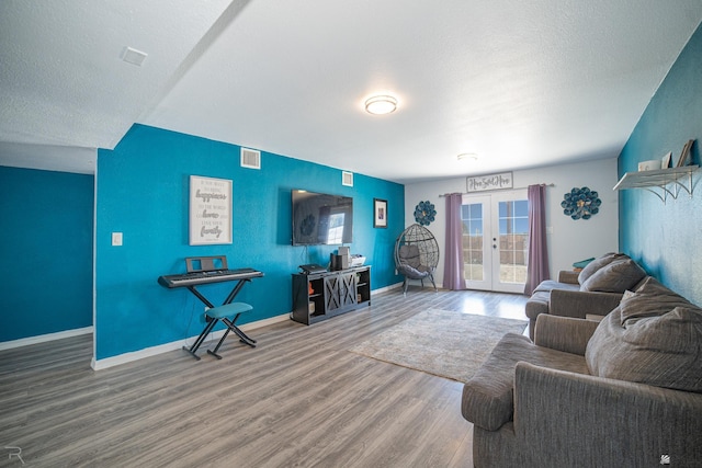 living room with a textured ceiling, french doors, and wood-type flooring