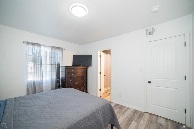 bedroom featuring ensuite bathroom and light wood-type flooring