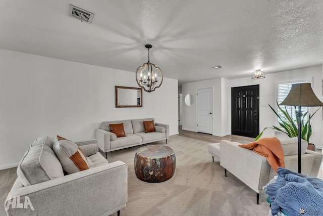 living room featuring a textured ceiling, a chandelier, visible vents, and baseboards