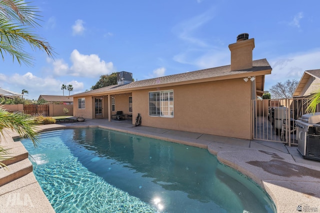 view of swimming pool with area for grilling and fence