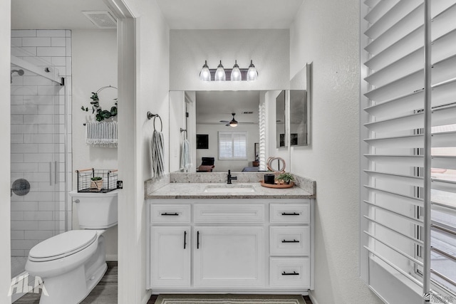 full bathroom featuring ceiling fan, a textured wall, toilet, vanity, and visible vents