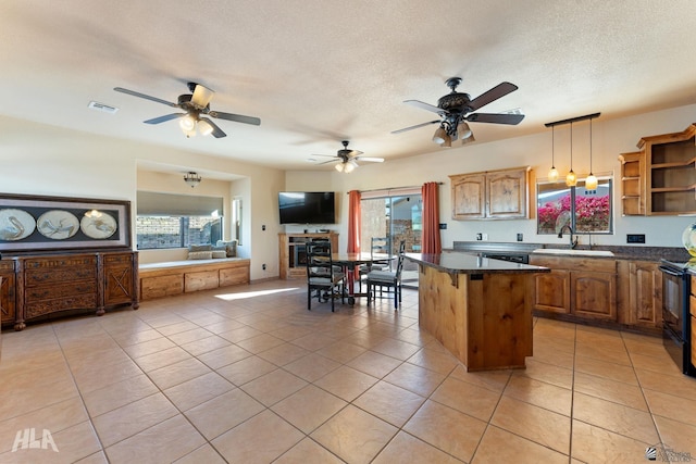 kitchen with sink, hanging light fixtures, a kitchen island, a textured ceiling, and light tile patterned flooring