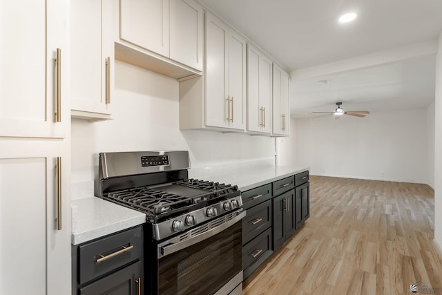 kitchen with white cabinetry, stainless steel gas stove, ceiling fan, and light hardwood / wood-style flooring