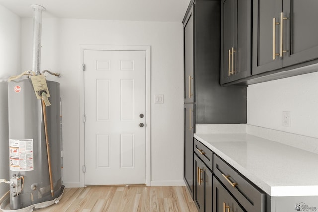 clothes washing area featuring gas water heater and light hardwood / wood-style flooring