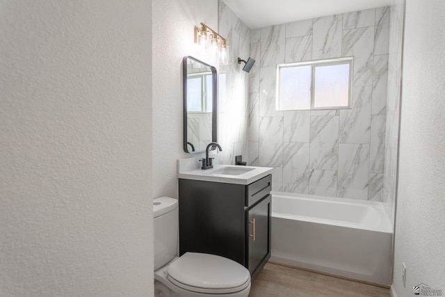 full bathroom featuring hardwood / wood-style flooring, vanity, tiled shower / bath combo, and toilet