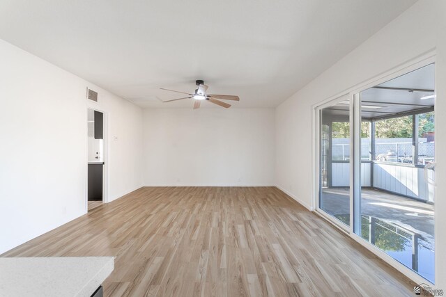 empty room featuring a wealth of natural light, light wood-type flooring, and ceiling fan