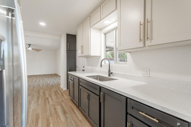 kitchen with stainless steel refrigerator, white cabinetry, sink, ceiling fan, and light hardwood / wood-style flooring