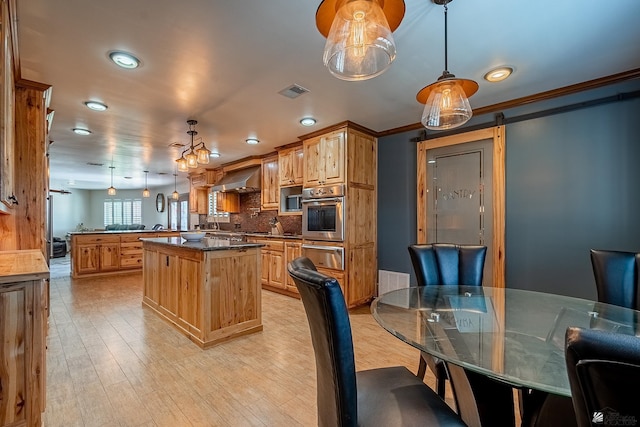 kitchen featuring a barn door, crown molding, oven, decorative light fixtures, and a kitchen island