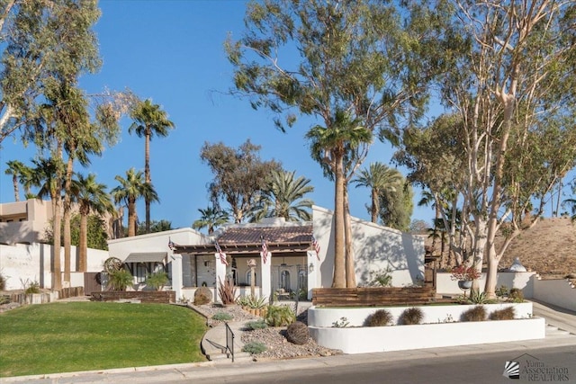 view of front of house with fence, a front lawn, and stucco siding