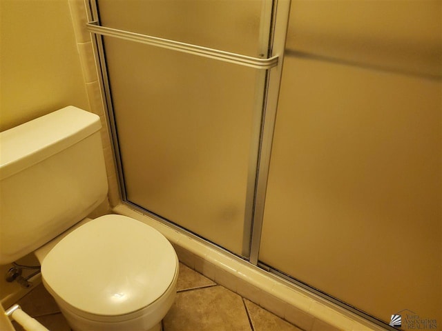 bathroom with tile patterned floors, toilet, and a shower with shower door