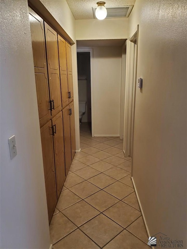 hallway with light tile patterned floors and a textured ceiling