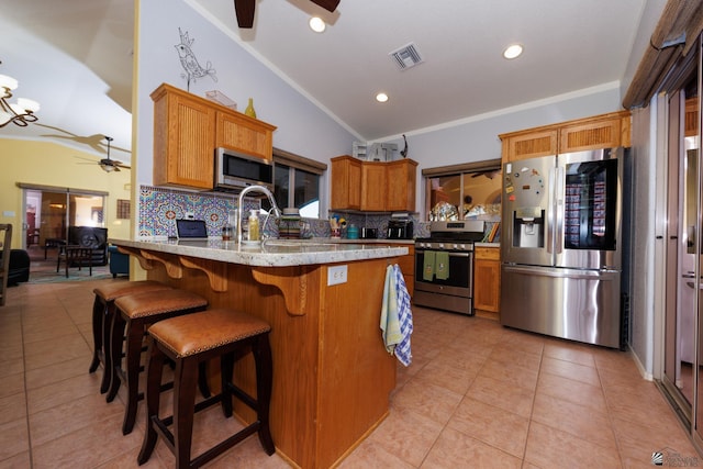 kitchen featuring sink, vaulted ceiling, appliances with stainless steel finishes, ceiling fan with notable chandelier, and backsplash