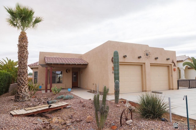 adobe home featuring stucco siding, driveway, an attached garage, and a tiled roof