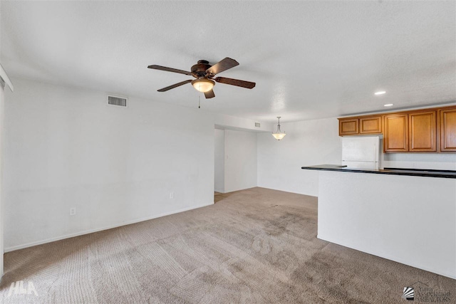 unfurnished living room with ceiling fan, light colored carpet, and a textured ceiling