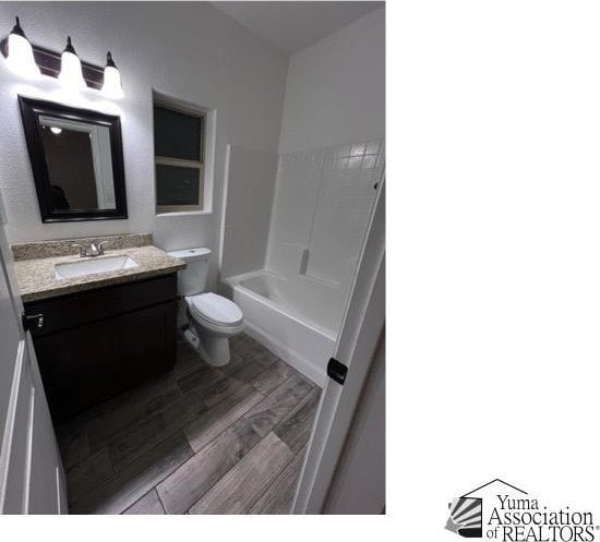 full bathroom featuring washtub / shower combination, wood-type flooring, toilet, and vanity