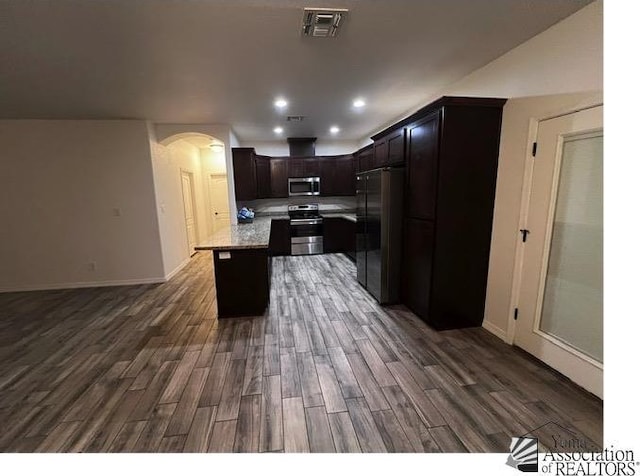 kitchen featuring a kitchen island, dark hardwood / wood-style flooring, light stone counters, stainless steel appliances, and dark brown cabinets