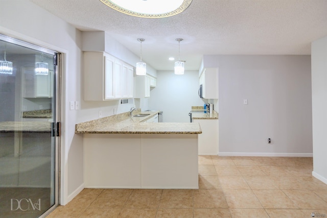 kitchen with white cabinetry, sink, light stone countertops, kitchen peninsula, and a textured ceiling