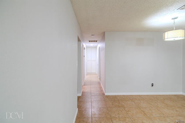 hall with light tile patterned floors and a textured ceiling