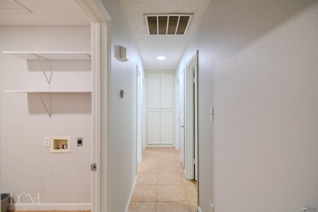 hallway with light tile patterned floors and a textured ceiling