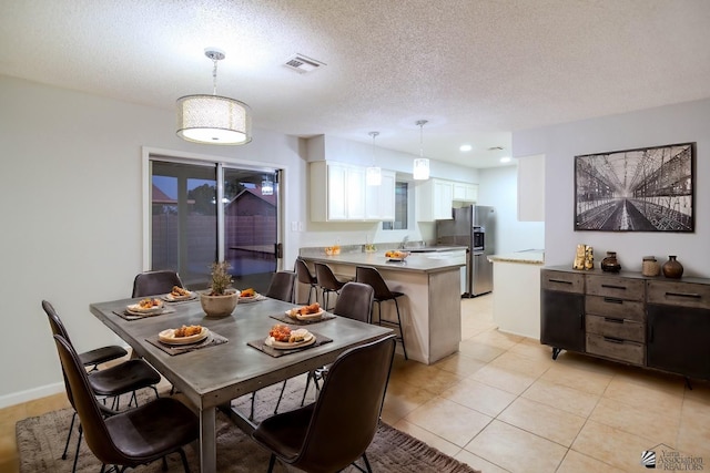 dining area featuring light tile patterned floors, a textured ceiling, and sink