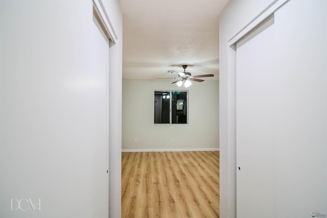 interior space featuring light wood-type flooring, a textured ceiling, and ceiling fan