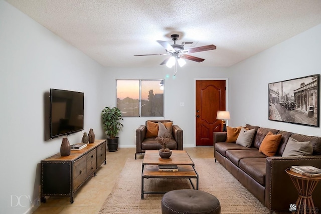 living room featuring ceiling fan, light tile patterned flooring, and a textured ceiling