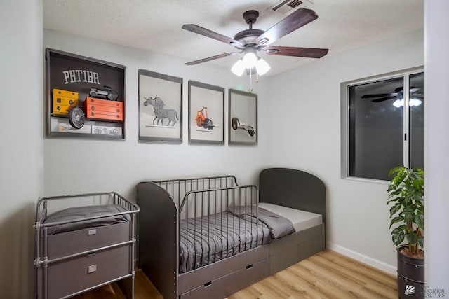 sitting room with ceiling fan, wood-type flooring, and a textured ceiling