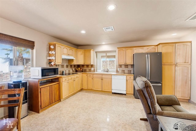 kitchen featuring stainless steel refrigerator, dishwasher, light brown cabinets, backsplash, and black electric stovetop