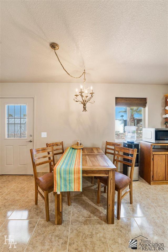 dining room featuring a notable chandelier, plenty of natural light, and a textured ceiling