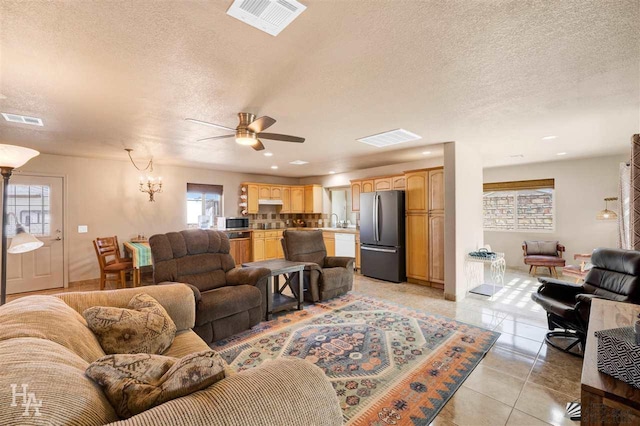 living room featuring light tile patterned floors, ceiling fan with notable chandelier, a textured ceiling, and sink