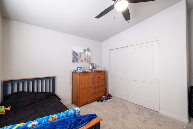 bedroom featuring lofted ceiling, light colored carpet, a ceiling fan, baseboards, and a closet