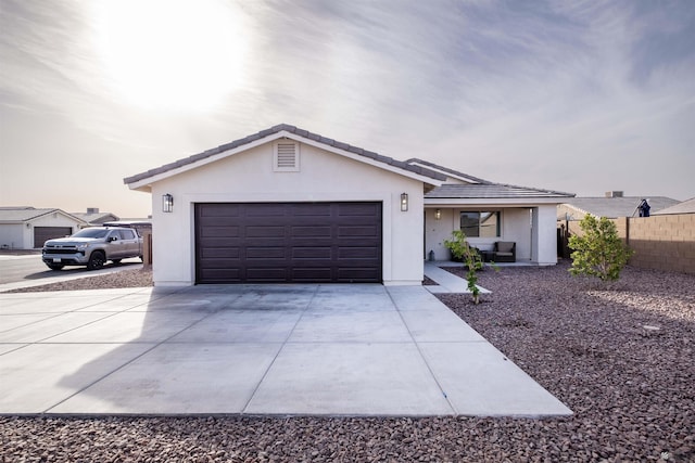 single story home with a garage, concrete driveway, a tiled roof, fence, and stucco siding