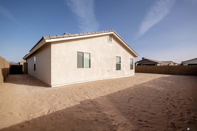 rear view of property featuring a fenced backyard and stucco siding