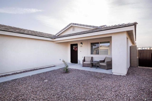 view of front of home featuring fence, a porch, and stucco siding