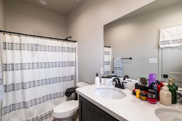 full bath with toilet, curtained shower, double vanity, and a sink