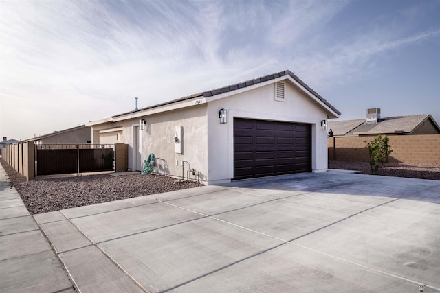 view of home's exterior with fence, concrete driveway, and stucco siding