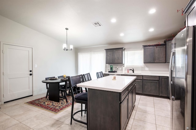 kitchen featuring a kitchen island, visible vents, a sink, light countertops, and freestanding refrigerator