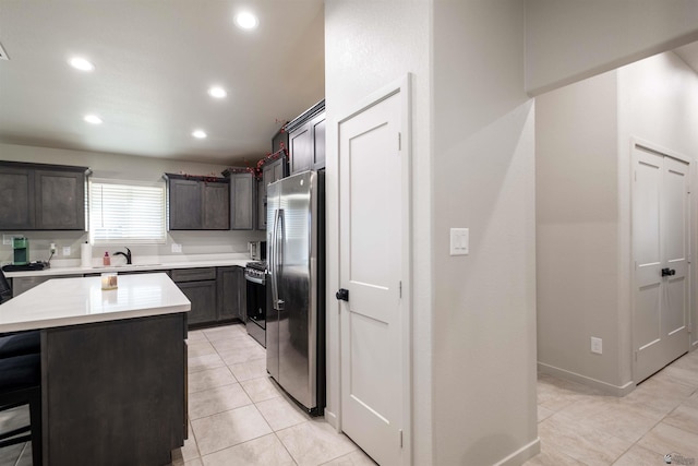 kitchen with recessed lighting, light countertops, freestanding refrigerator, gas stove, and a kitchen island