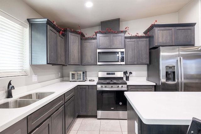 kitchen featuring recessed lighting, light countertops, appliances with stainless steel finishes, light tile patterned flooring, and a sink