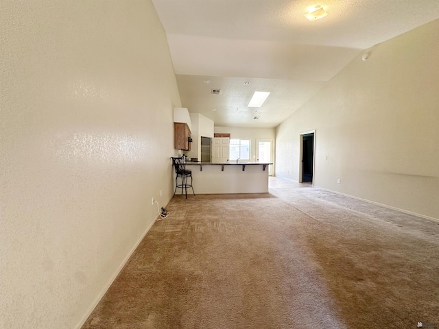 unfurnished living room featuring light colored carpet, sink, and high vaulted ceiling