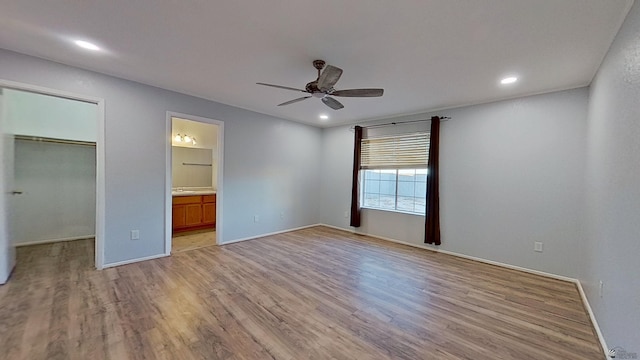 unfurnished bedroom with connected bathroom, light wood-style flooring, recessed lighting, a ceiling fan, and a spacious closet