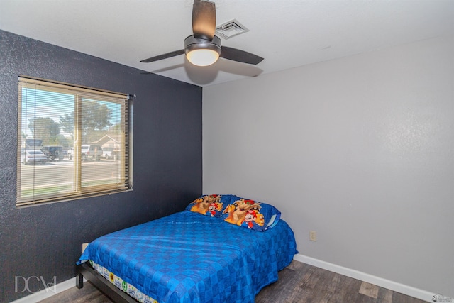 bedroom featuring visible vents, ceiling fan, baseboards, and wood finished floors