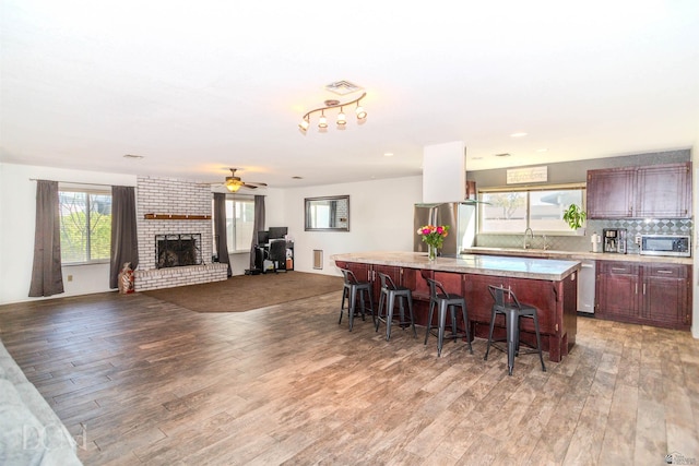 kitchen featuring a breakfast bar, a center island, light countertops, stainless steel appliances, and a sink