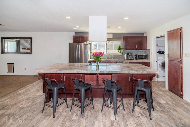 kitchen featuring tasteful backsplash, washer / clothes dryer, a breakfast bar, stainless steel appliances, and a sink