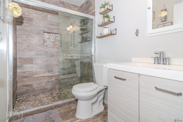 full bath with wood finished floors, a stall shower, vanity, and toilet